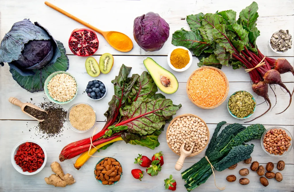 Assorted nutritious foods for eating healthy, including red cabbage, avocado, lentils, oats, blueberries, kiwi, beets, almonds, leafy greens and seeds.