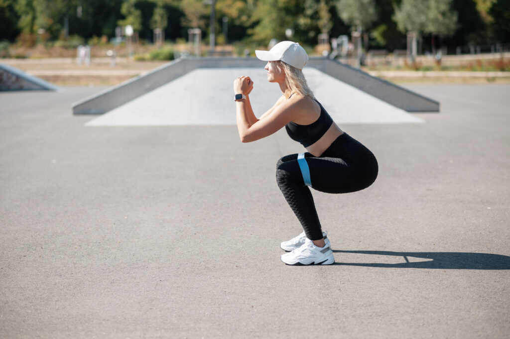 Woman performing a bodyweight squat outdoors, demonstrating exercises to promote optimized heart health through an active lifestyle.