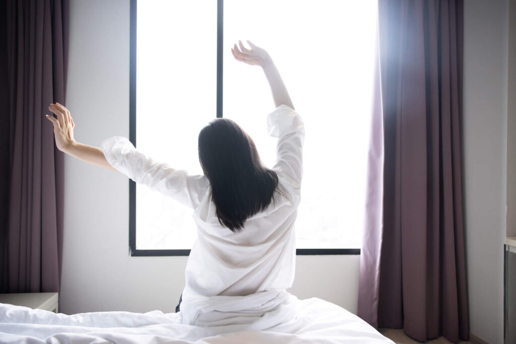 A woman stretching in the morning after a good night's sleep and practicing it daily to rest well as a part of the prevention of Alzheimer's.