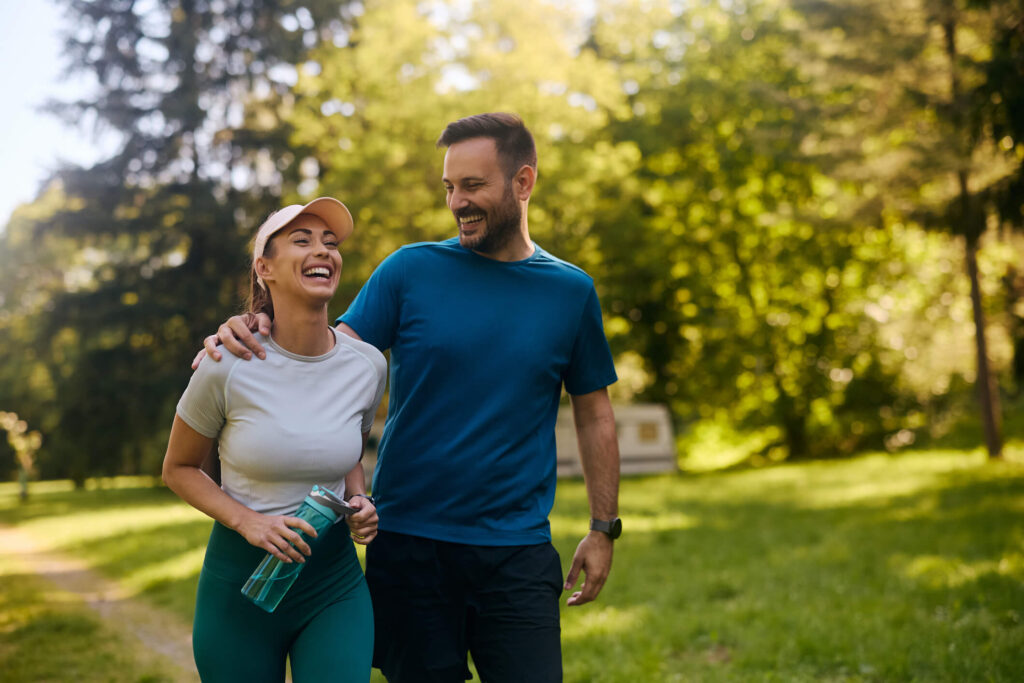 A smiling couple walking outdoors, showing how a balanced diet and regular physical activity support wellness and help prevent nutrient deficiencies.